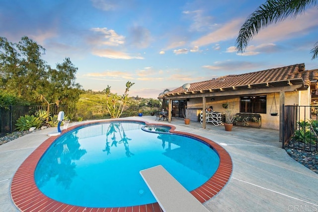 pool at dusk with a diving board and a patio area