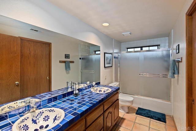 full bathroom with vanity, tile patterned floors, toilet, and combined bath / shower with glass door