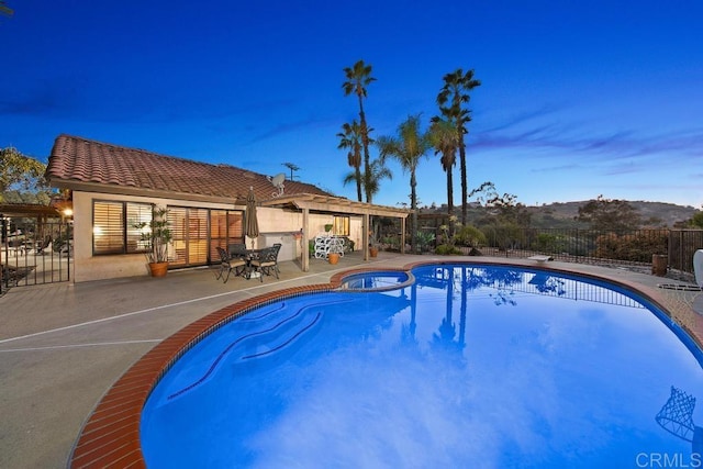 pool at dusk with a patio area and a mountain view