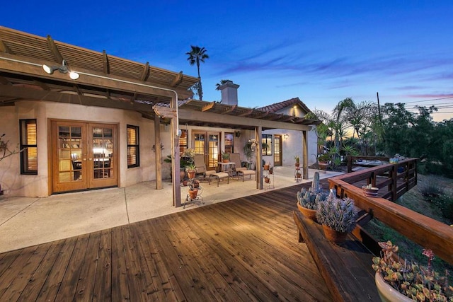 deck at dusk featuring french doors and a patio area