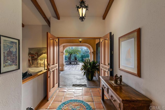 tiled entryway featuring beamed ceiling