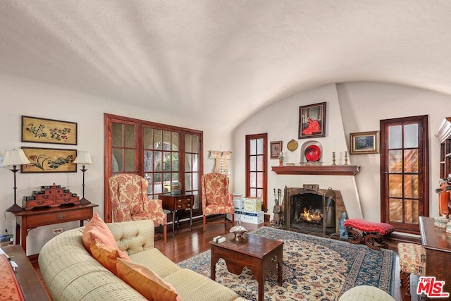 living room with wood-type flooring, lofted ceiling, and a textured ceiling