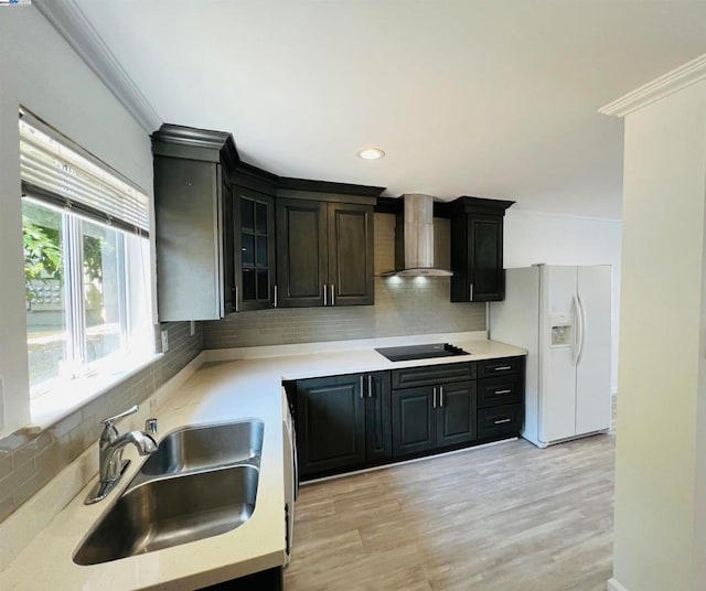 kitchen with wall chimney range hood, decorative backsplash, black electric cooktop, sink, and white refrigerator with ice dispenser