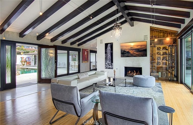 living room with a chandelier, light hardwood / wood-style flooring, and lofted ceiling with beams