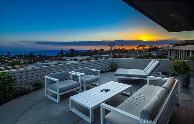 patio terrace at dusk with an outdoor hangout area and a water view