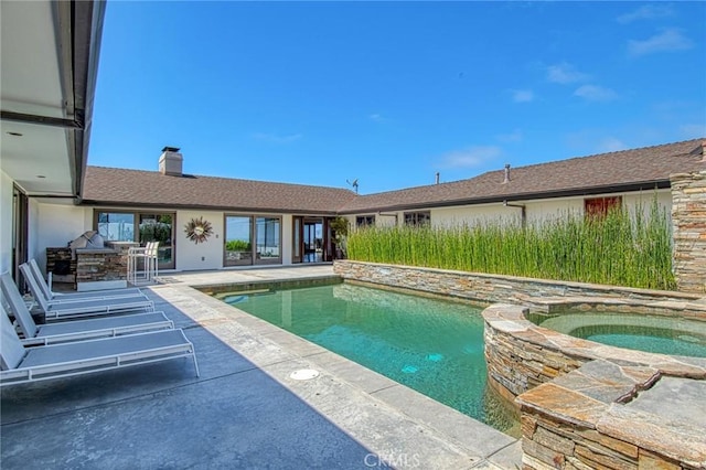 view of swimming pool featuring an in ground hot tub, exterior kitchen, and a patio