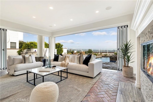 living room featuring a stone fireplace, a water view, and crown molding