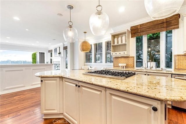 kitchen with light stone countertops, appliances with stainless steel finishes, light wood-type flooring, and decorative light fixtures