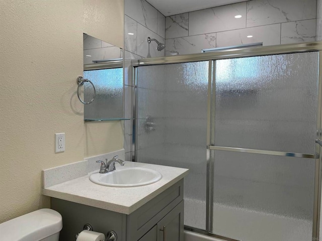 bathroom featuring vanity, walk in shower, and toilet