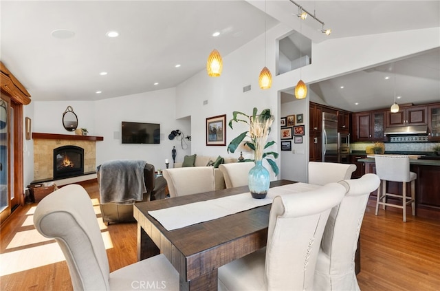 dining area with light wood-style floors, recessed lighting, visible vents, and a tile fireplace