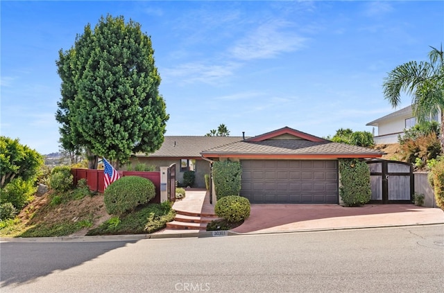 ranch-style home with driveway, an attached garage, and fence