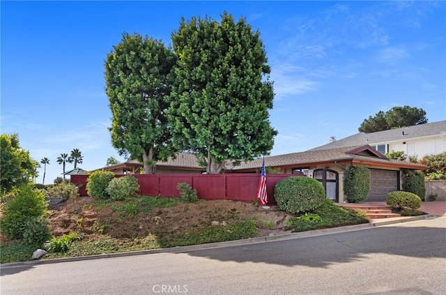 ranch-style house featuring an attached garage and fence