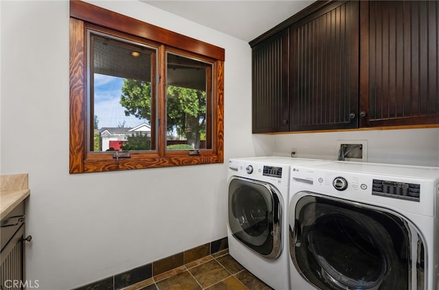 clothes washing area with dark tile patterned flooring, cabinet space, independent washer and dryer, and baseboards