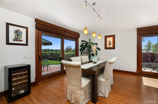 dining space featuring beverage cooler, wood finished floors, and a wealth of natural light