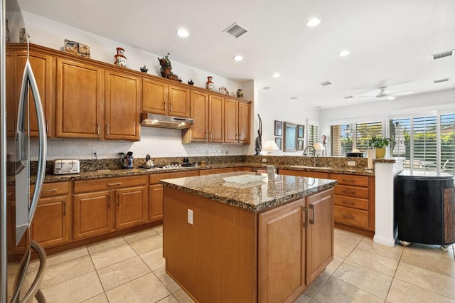 kitchen featuring dark stone counters, ceiling fan, a kitchen island, kitchen peninsula, and stainless steel appliances