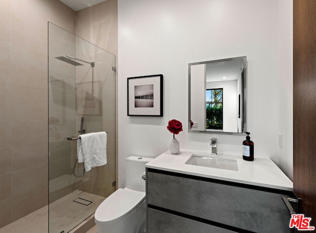 bathroom with vanity, tiled shower, and toilet