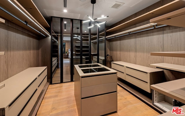 walk in closet with light wood-type flooring and a chandelier