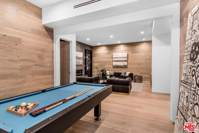 playroom with light wood-type flooring, wood walls, a stone fireplace, and billiards