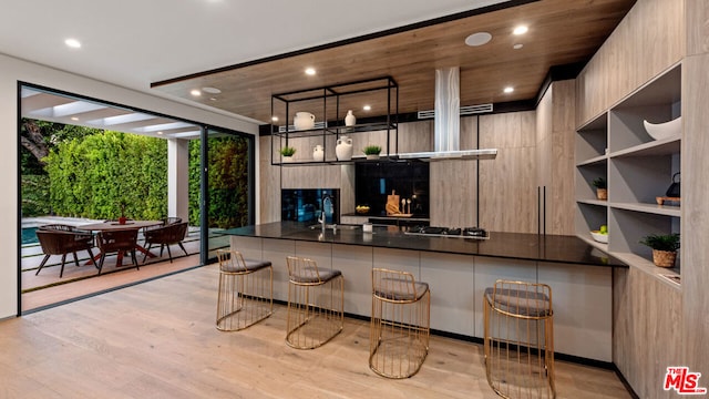 kitchen featuring expansive windows, kitchen peninsula, light wood-type flooring, and a kitchen breakfast bar