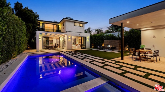 pool at dusk featuring a patio area