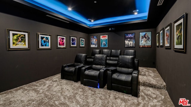 carpeted home theater with a tray ceiling