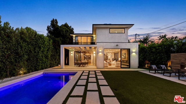 back house at dusk with a yard and a patio