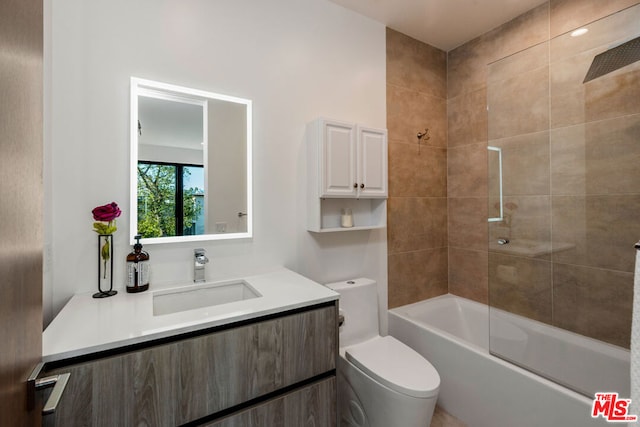 full bathroom featuring vanity, tiled shower / bath combo, and toilet