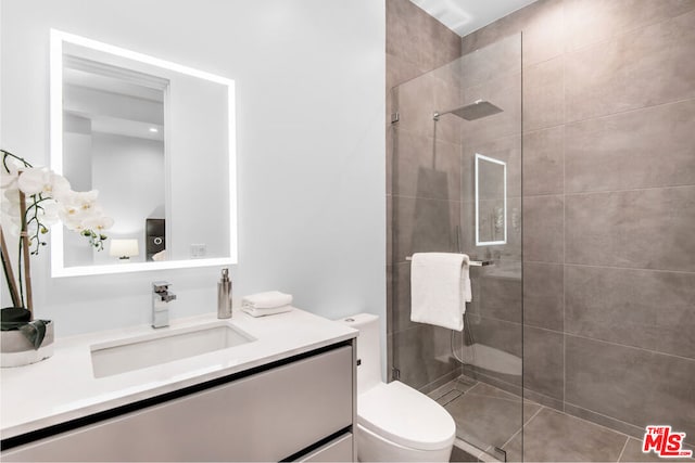 bathroom with tiled shower, vanity, and toilet