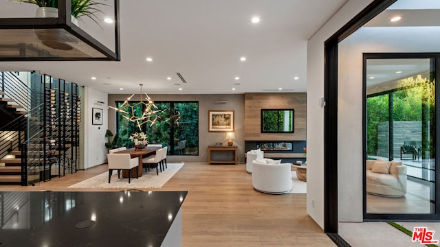 dining area with a notable chandelier, a large fireplace, and light hardwood / wood-style flooring