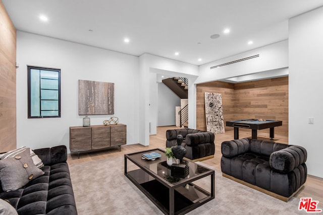 living room featuring pool table, wooden walls, and light hardwood / wood-style flooring