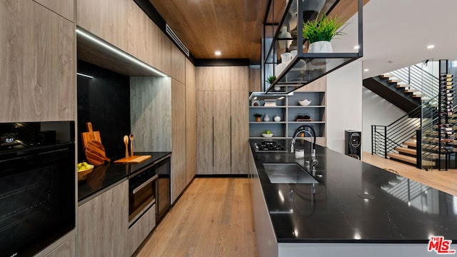 kitchen with light hardwood / wood-style floors, black appliances, and sink