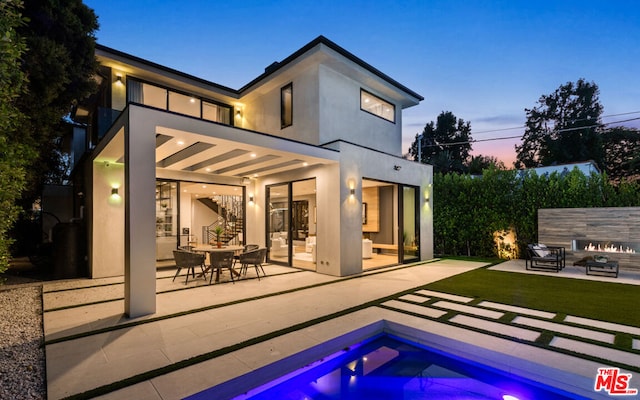 pool at dusk featuring a yard and a patio area