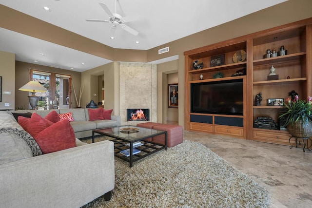 living room with ceiling fan, built in features, and a premium fireplace