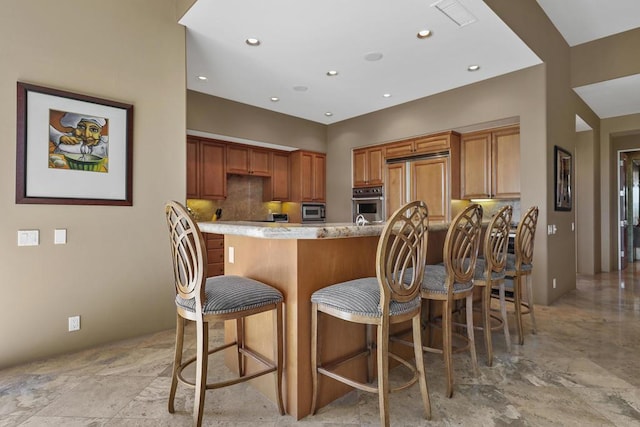 kitchen with a kitchen breakfast bar, light stone countertops, and stainless steel oven