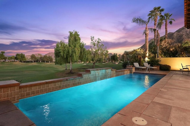 pool at dusk featuring a yard and a patio area