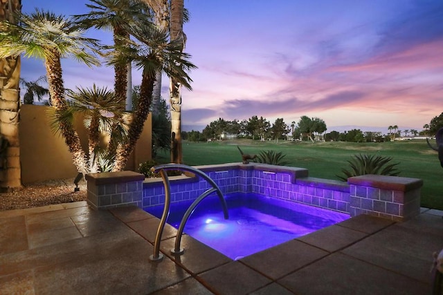 pool at dusk with an in ground hot tub and a yard