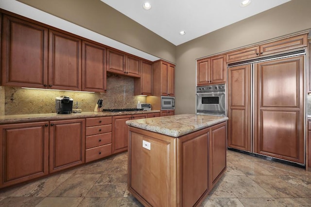 kitchen with backsplash, built in appliances, light stone countertops, and a center island