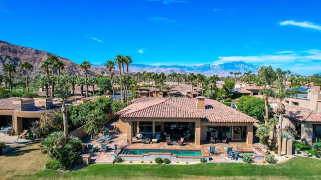 back of property with a mountain view and a patio