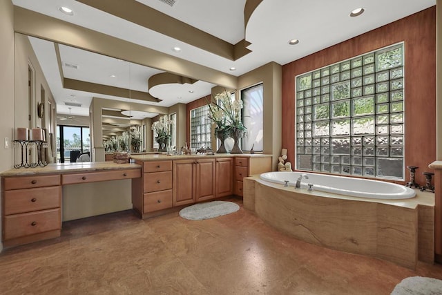 bathroom with plenty of natural light, vanity, and tiled tub