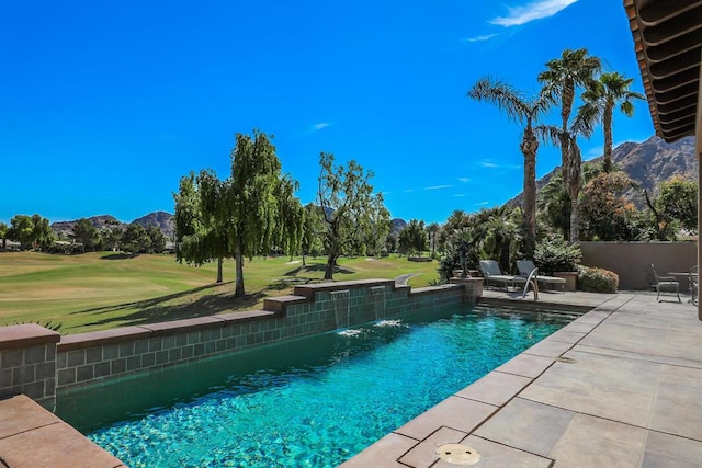 view of swimming pool with pool water feature, a mountain view, a yard, and a patio