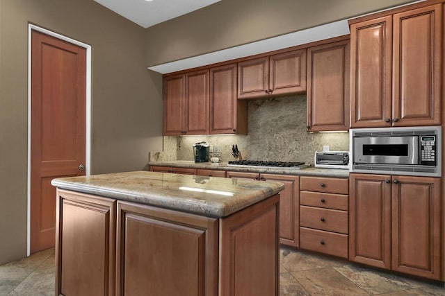 kitchen featuring decorative backsplash, stainless steel appliances, a kitchen island, and light stone countertops