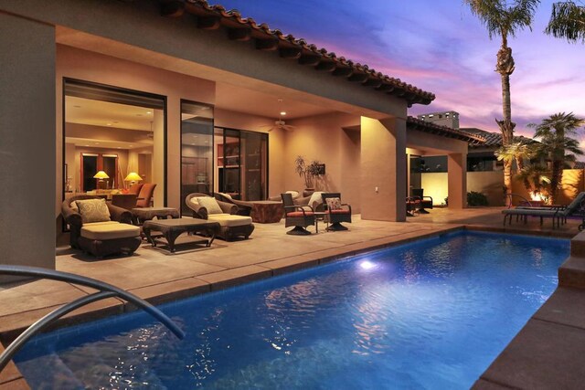 pool at dusk with a patio area, ceiling fan, and an outdoor hangout area