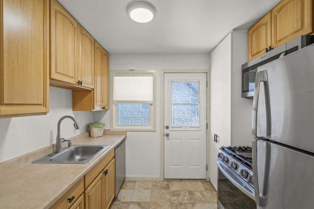 kitchen with appliances with stainless steel finishes, sink, and light brown cabinetry