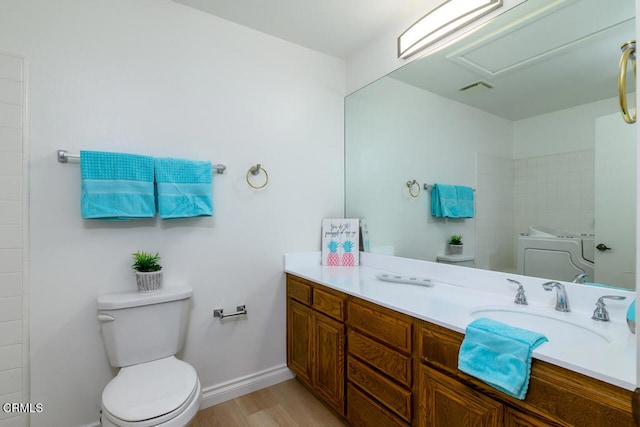 bathroom with washer / clothes dryer, hardwood / wood-style floors, vanity, and toilet