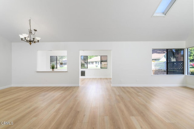 unfurnished living room featuring a skylight, light wood-type flooring, and an inviting chandelier