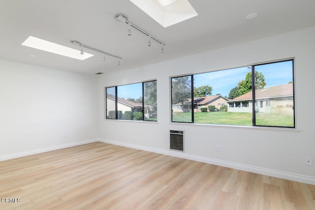 spare room with a skylight, light wood-type flooring, and track lighting