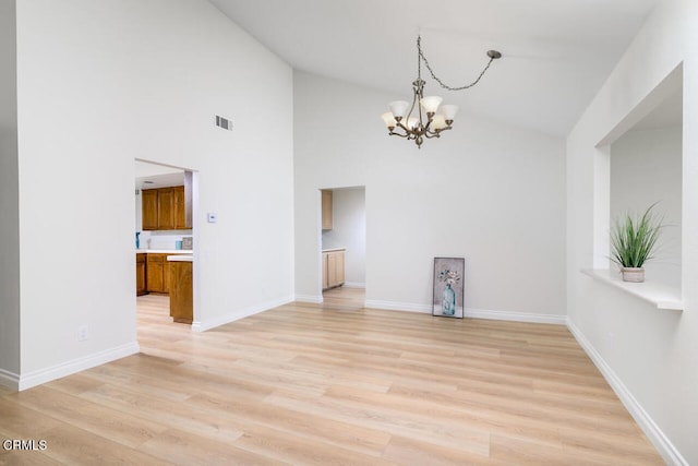 interior space featuring light wood-type flooring, a notable chandelier, and a towering ceiling