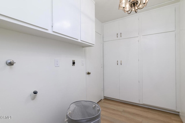 laundry area with hookup for an electric dryer, a chandelier, light hardwood / wood-style floors, and cabinets