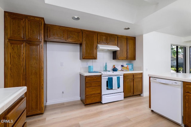 kitchen with tasteful backsplash, white appliances, and light hardwood / wood-style flooring