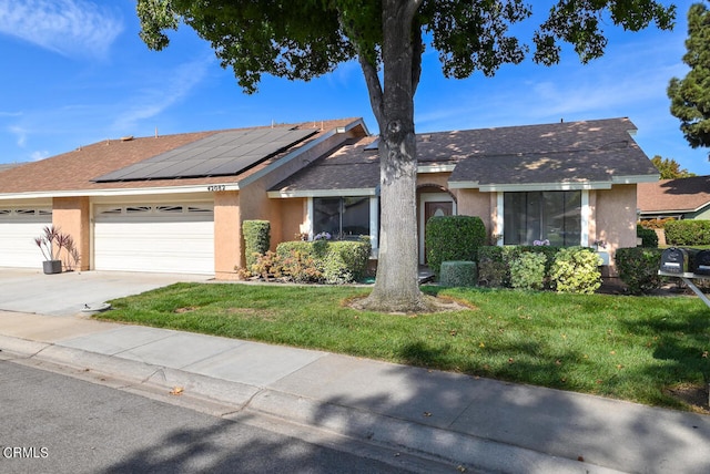 ranch-style house featuring solar panels, a front yard, and a garage